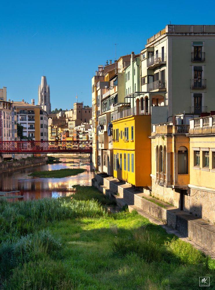 Color photo of colorful buildings along a curving, shallow river.