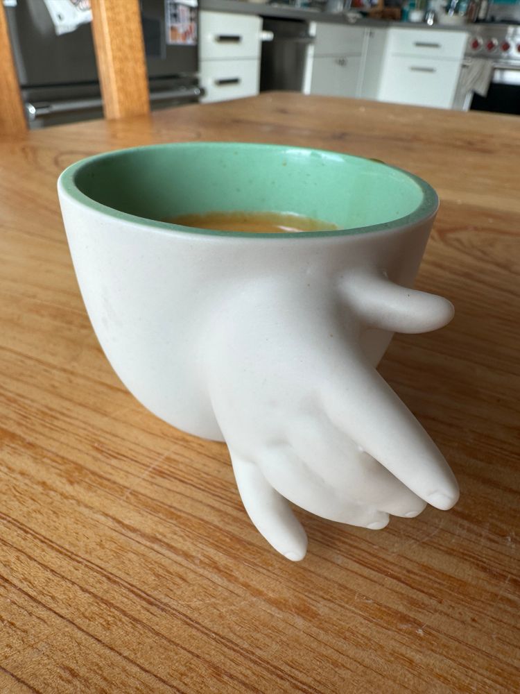 Sitting on a wooden table is a cup. Out stretched from one side of the cup is a little baby hand. The hand is intended to be the handle of the cup. But it is awkwardly designed and looks like the disembodied hand of a baby that is going climb through the cup or pull you into it.

… it was a gift from my mother-in-law. She thought it was cute.


