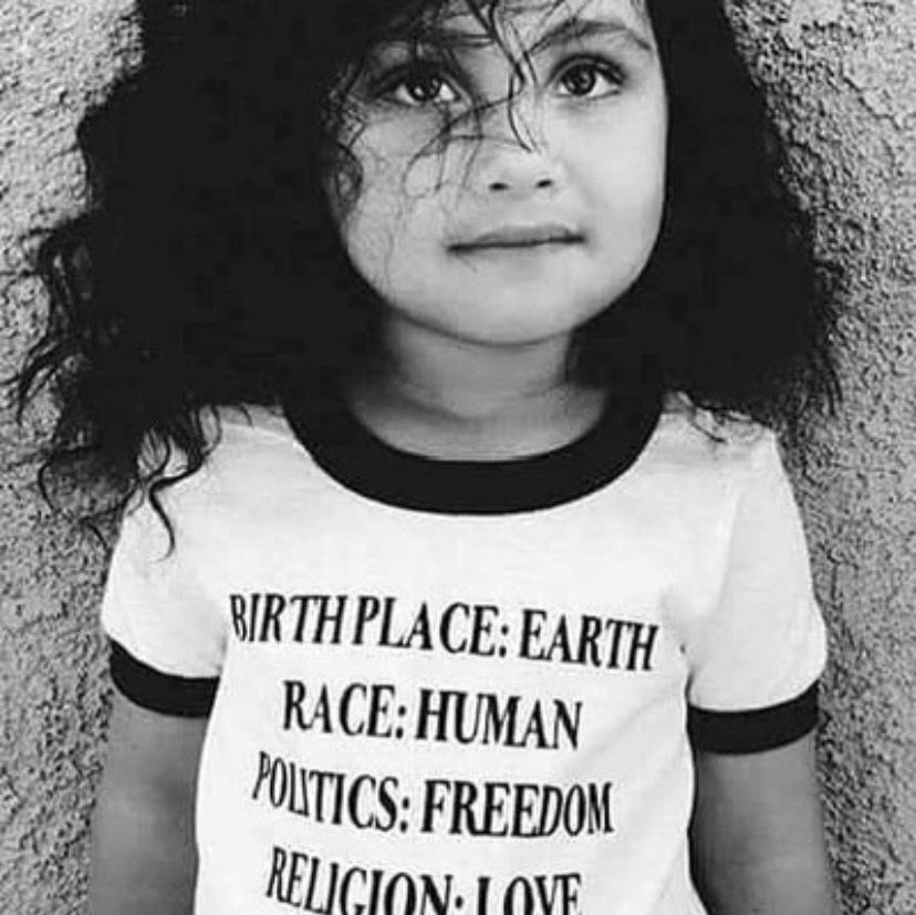 Little girl wearing a T-shirt that says: BIRTH PLACE: EARTH RACE: HUMAN POLITICS: FREEDOM RELIGION: LOVE