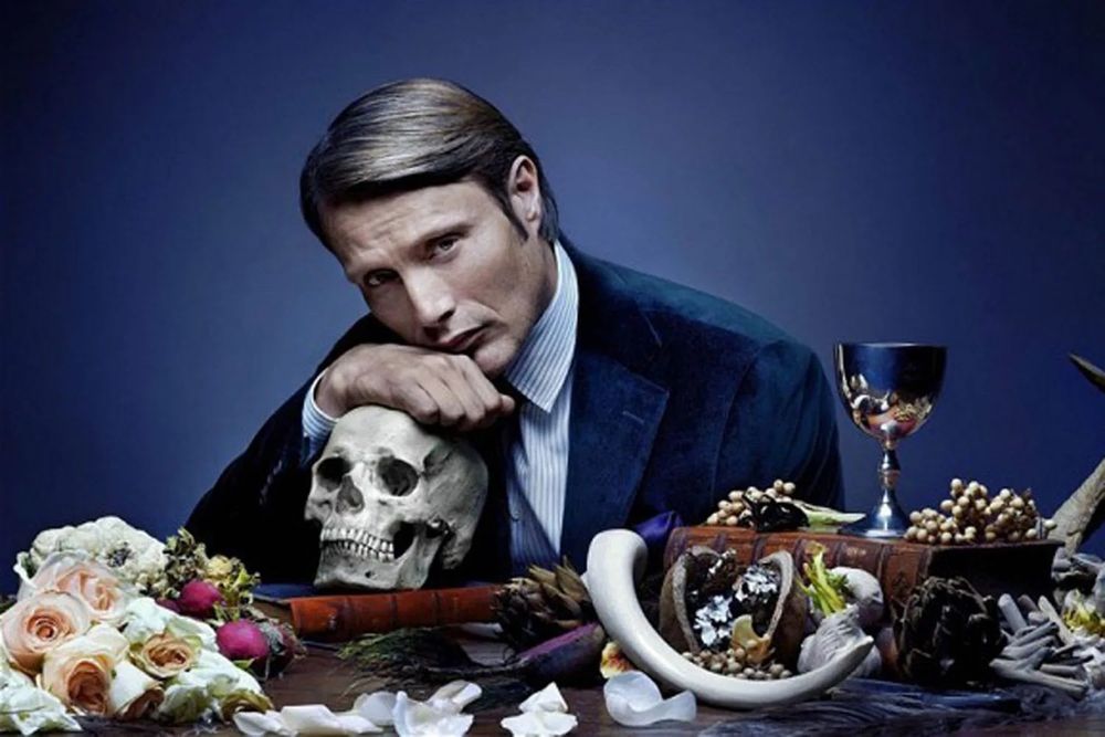 Mads Mikkelsen as Hannibal Lecter, leaning on a skull
