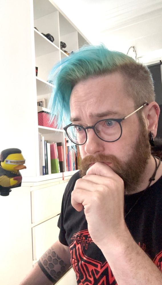 A duck in a Starfleet costume stares at Michael while he’s nervously looking at a screen 