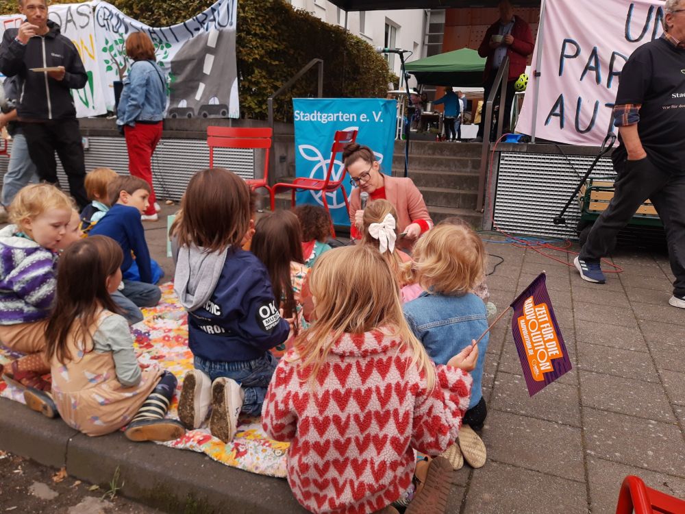 Katja Diehl stellt Kindern ihr Buch vor, diese sitzen vor ihr auf einer Picknickdecke