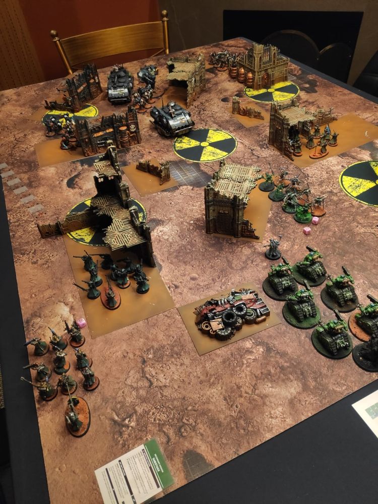 Imagem de mesa com uma partida de warhammer 40k acontecendo.