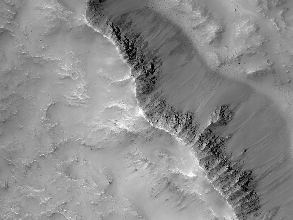 Image shows the rim of an impact crater on Mars with exposed rocks near the top of the rim that extend a bit down the crater wall. (NASA/JPL-Caltech/University of Arizona)