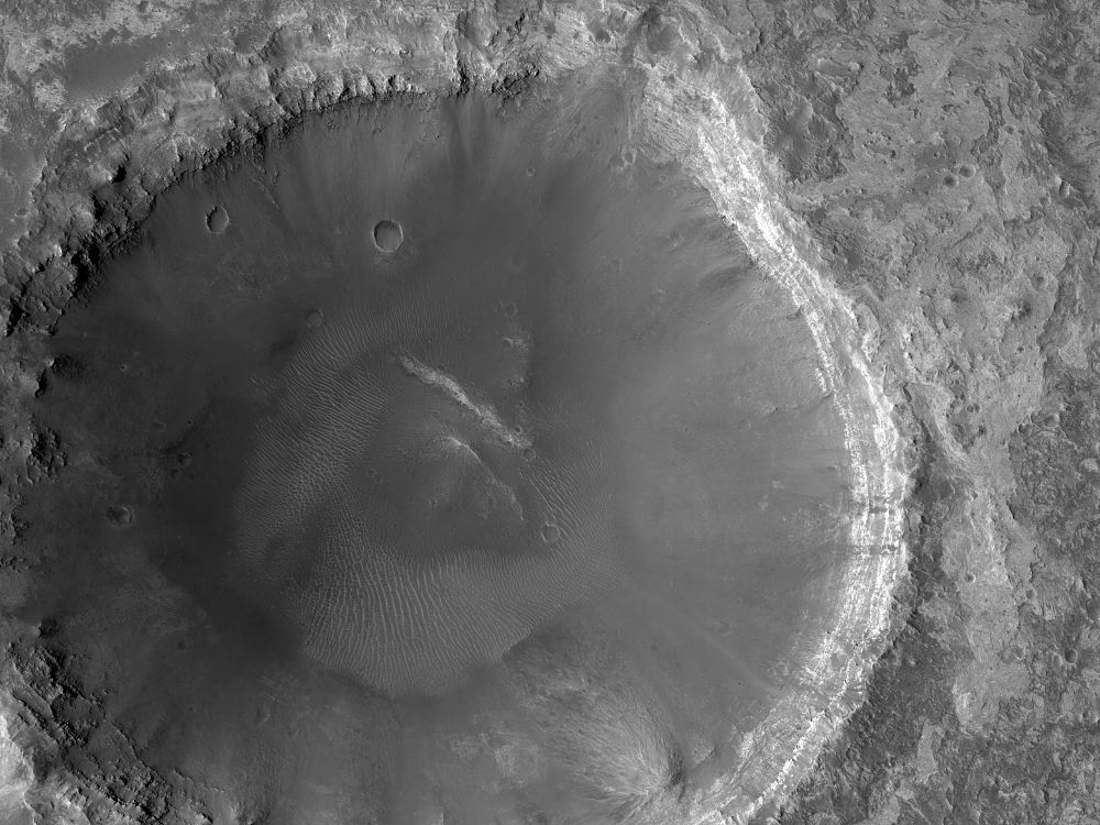 Image shows a large, under 5-km diameter impact crater on the surface of Mars. There are bright exposures of bedrock on the rim in one section of the crater, and some darker streaks down one side. (NASA/JPL-Caltech/University of Arizona)