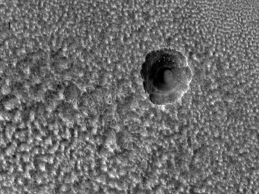 Image cutout shows a small impact crater on Mars that has expanded due to the sublimation of ice. The scene is less than 5 km, 3 miles, across. (NASA/JPL-Caltech/University of Arizona)