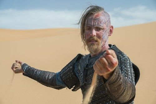 Halfdan kneels in the sand and lets it flow from his hands