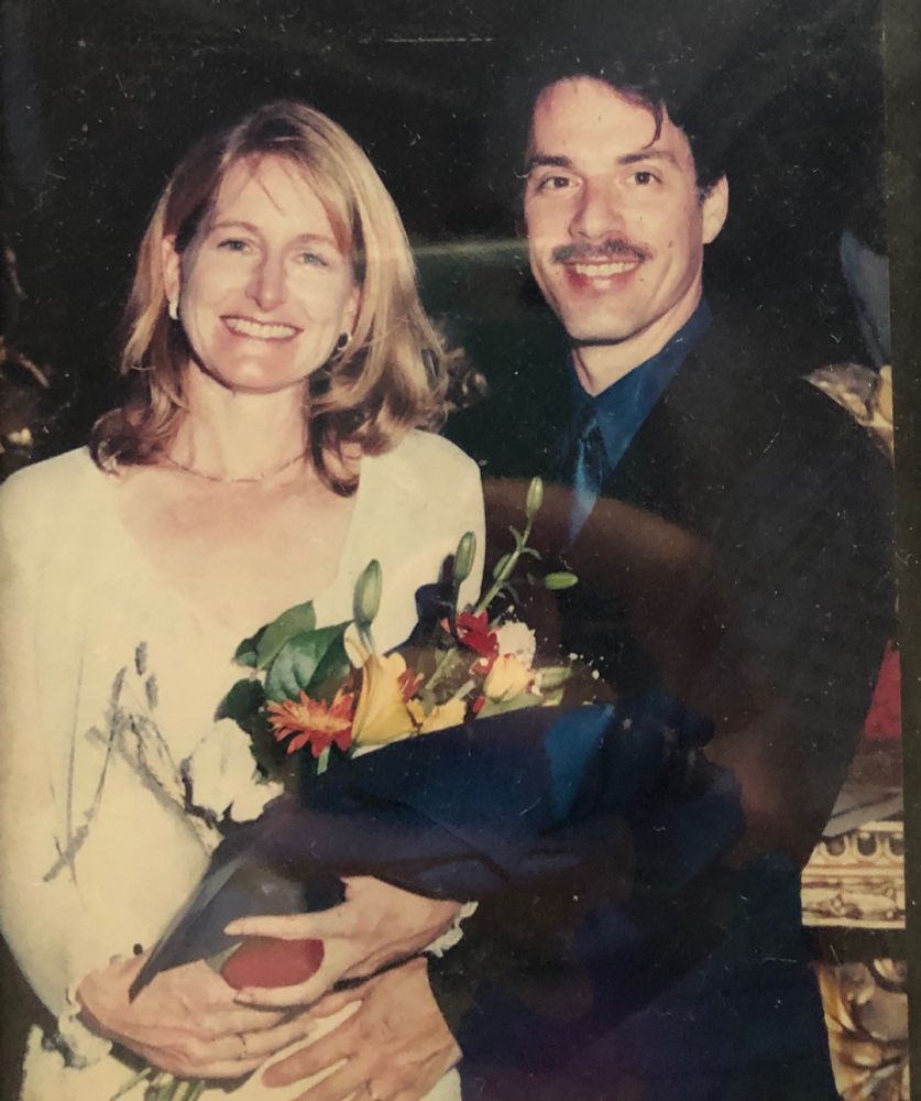 Blonde cis woman and dark haired cis man with porn stache he was eventually shamed into shaving smiling at city hall in Florence while getting married without any family around 