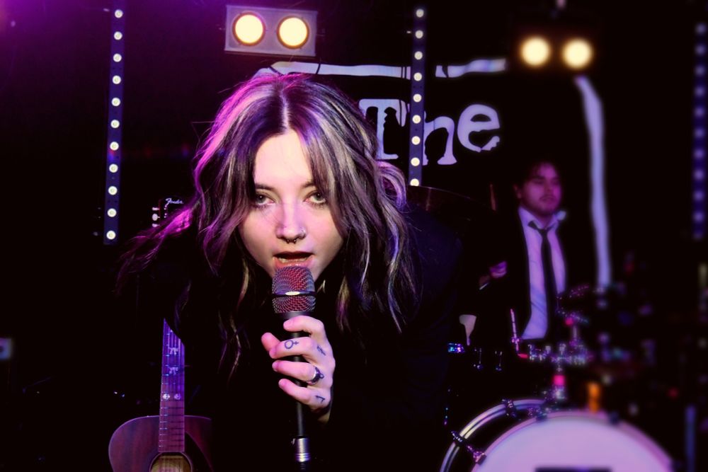 Close up shot of Crysometimes on stage at The Hope & Ruin in Brighton, singer holding the mic and leaning forward straight to camera