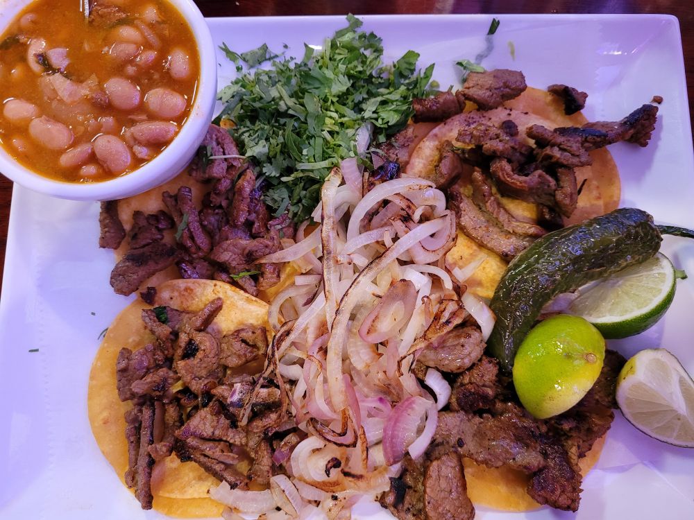 Sick Pic of tacos al pastor garnished with sautéed onions, cilantro and a jalapeño torreado. Comes with a small bowl of charro beans. Found in Corpus Christi, Texas