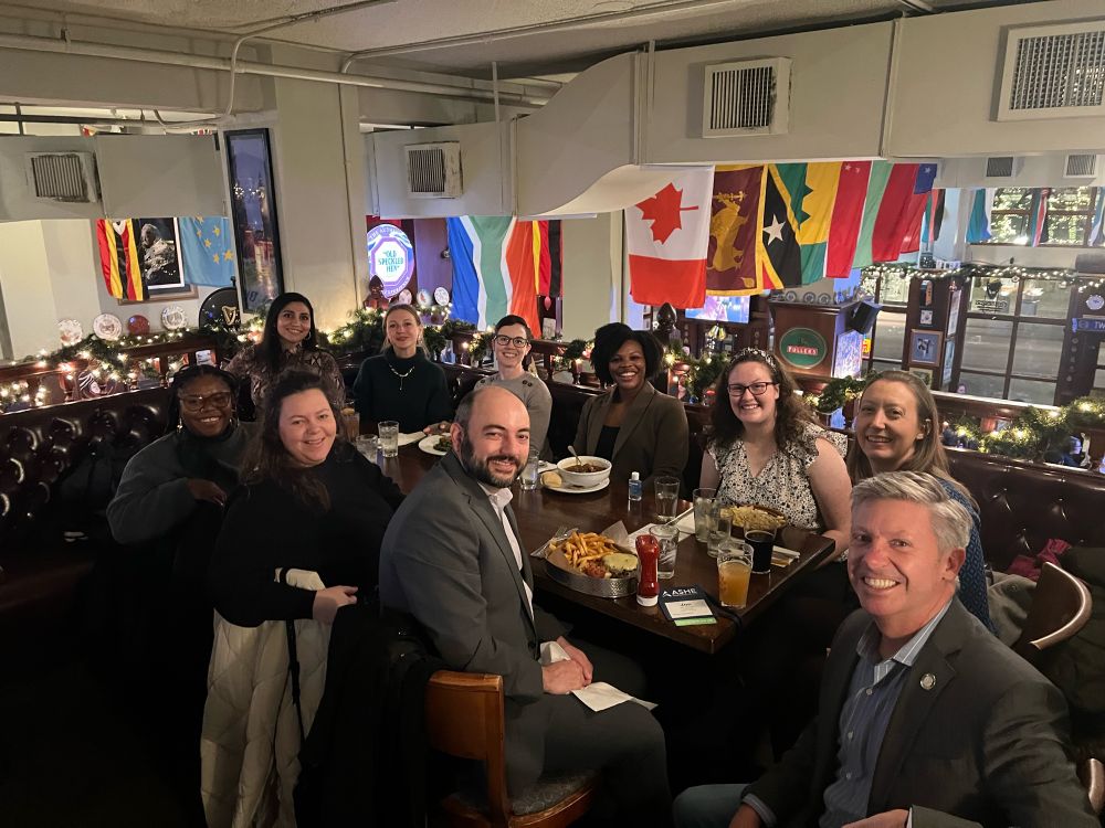 A group of faculty, students, and alumni from the William & Mary Higher Education Program seated around a table for dinner 