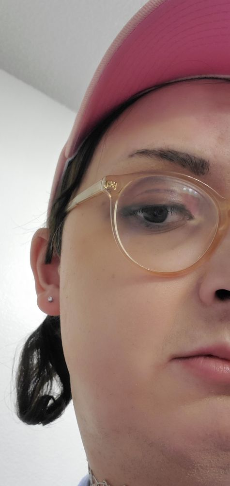 Vivian with a rough twintail and pink hat showing off her pierced ear with an earring in it