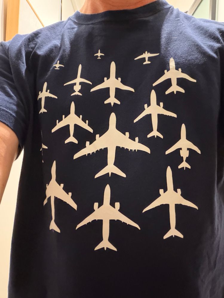 Photo of a t-shirt printed with a bunch of different sized commercial planes with a 747 in the middle, a DC-8 and a bunch of twin jets. 