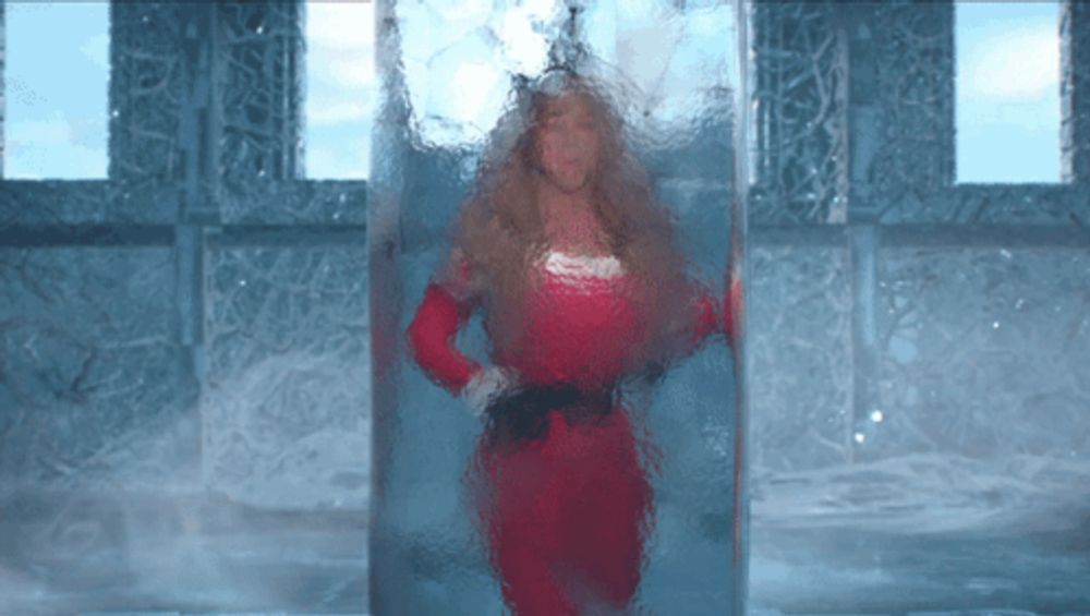 a woman in a red dress is standing in a glass container