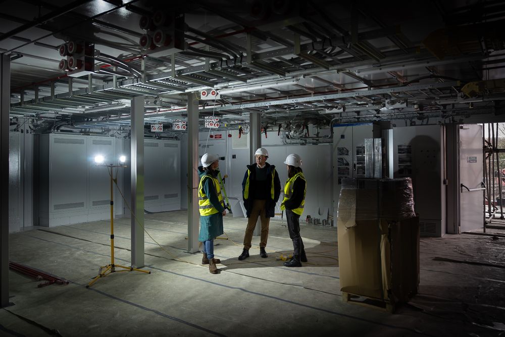 Three colleagues stand inside a part of the building site of Isambard-AI