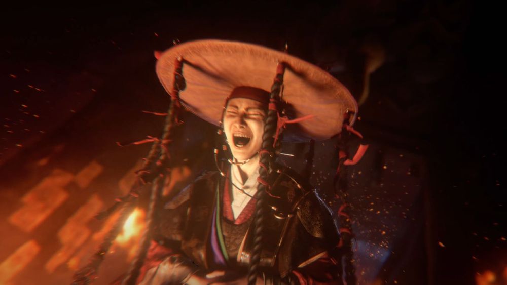 Myoan, a shaman woman from the Woochi the Wayfarer reveal trailer, laughing while flames explode around her. 