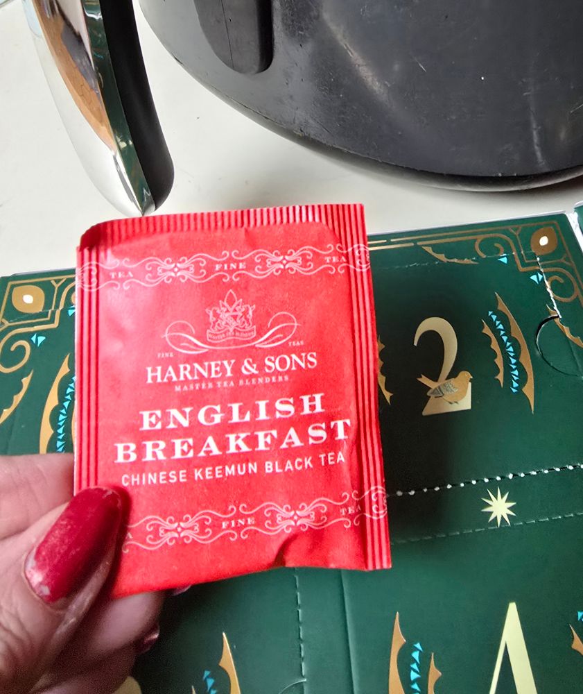Packet of Harney English Breakfast Tea in a red wrapper held beside the Day 2 slot of the Harney 12 Days of Christmas Tea Advent Calendar.