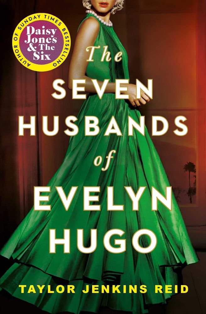 The book cover for The Seven Husbands of Evelyn Hugo by Taylor Jenkins Reid. A olive-skinned blonde woman with red lipsticks, a swishing green dress and a string of pearls around her neck stands in the centre of the cover. Her body and the bottom half of her face is visible. Behind her is a window in shadow. The book's title is in bold, white text in front of the window, and the author's name sits at the bottom of the cover in yellow font.