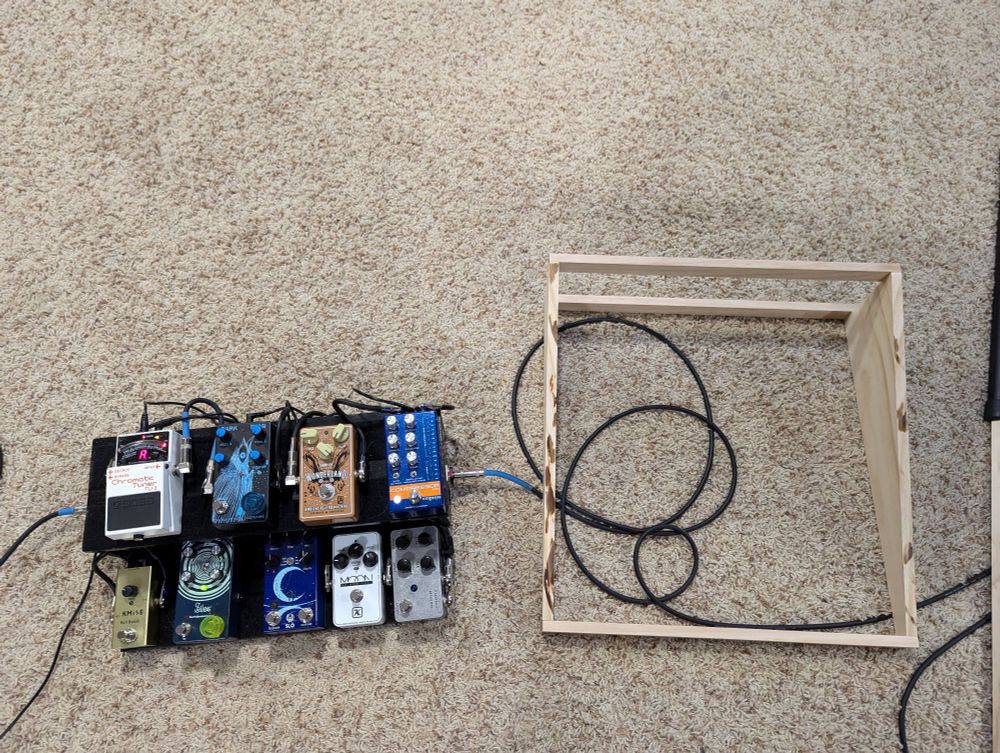 A guitar pedalboard next to a wooden frame of a future pedalboard.