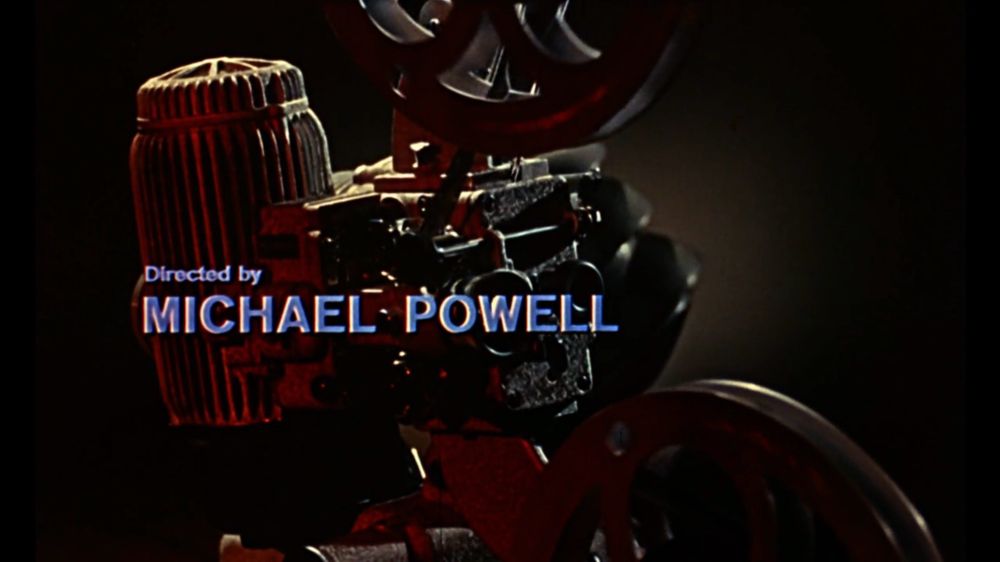 A movie projector in a white and red light. 
Text reads : « directed by Michael Powell »