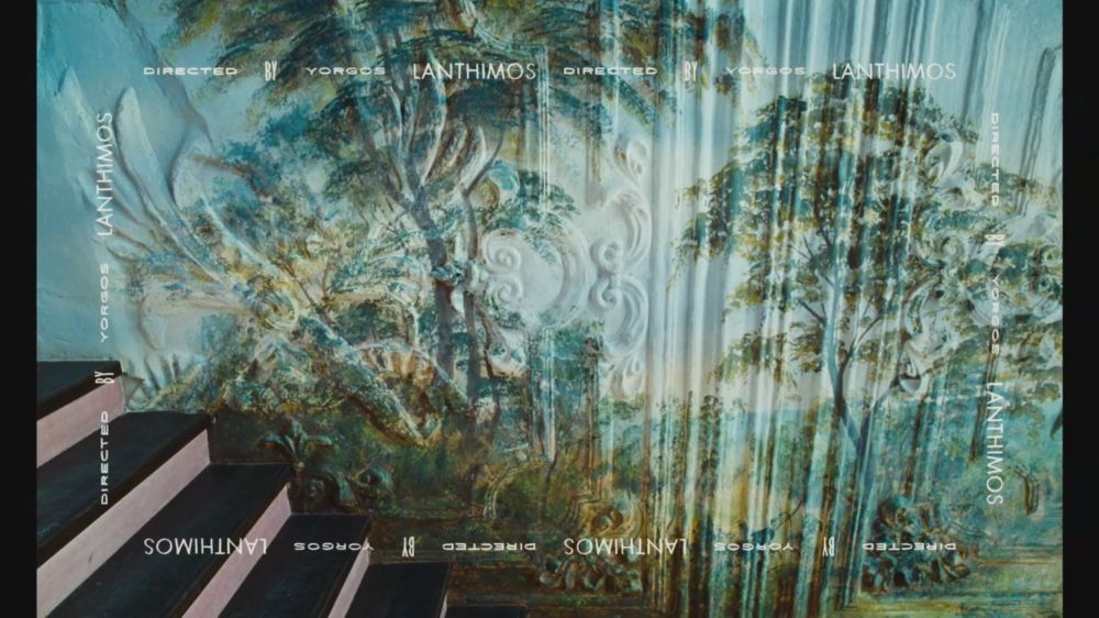 Credits from Poor Things (2023)
Some trees are painted on a wall. There are stairs on the bottom left. 
All around the image, text says in different font and sizes : “Directed by Yorgos Lanthimos“