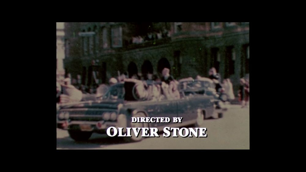 Credits from the movie JFK. 
Old footage of president Kennedy in his car before his assassination
Text says “directed by Oliver Stone“