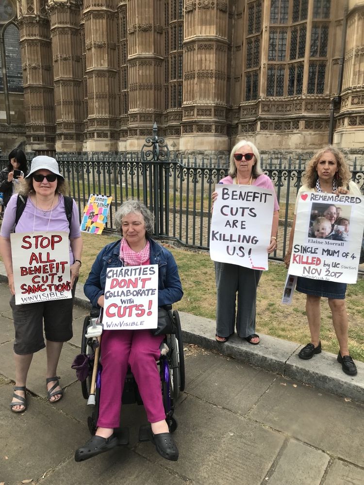 Four Disabled protestors outside Parliament. They have placards that read:
Stop all benefits cuts and sanctions, Winvisible
Charities don't collaborate with cuts, Winvisible
Benefit cuts are killing us!
Remembered: Elaine Morrall Single Mum of 4 killed by UC sanction, November 2017
Winvisible