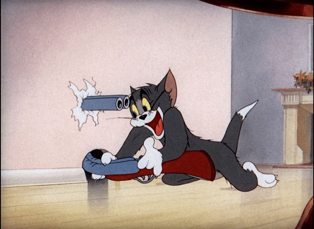 Tom from the cartoon “Tom and Jerry” puts a shotgun through hole in the wall, the barrel curves back towards him and is aiming at his head. Tom looks very pleased, thinking he’s going to shoot Jerry, who’s presumed to be inside the wall.