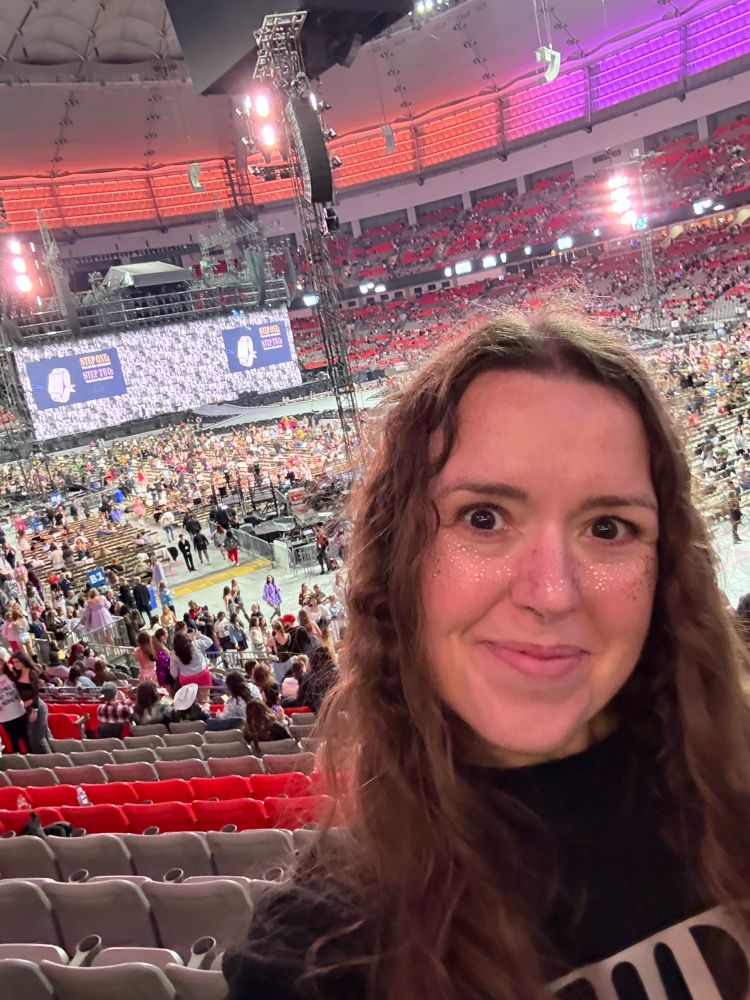 Photo of 43 year old woman taking a selfie with the eras tour stage behind her