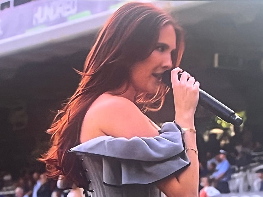 Mimi Webb singing into a mic at the cricket.