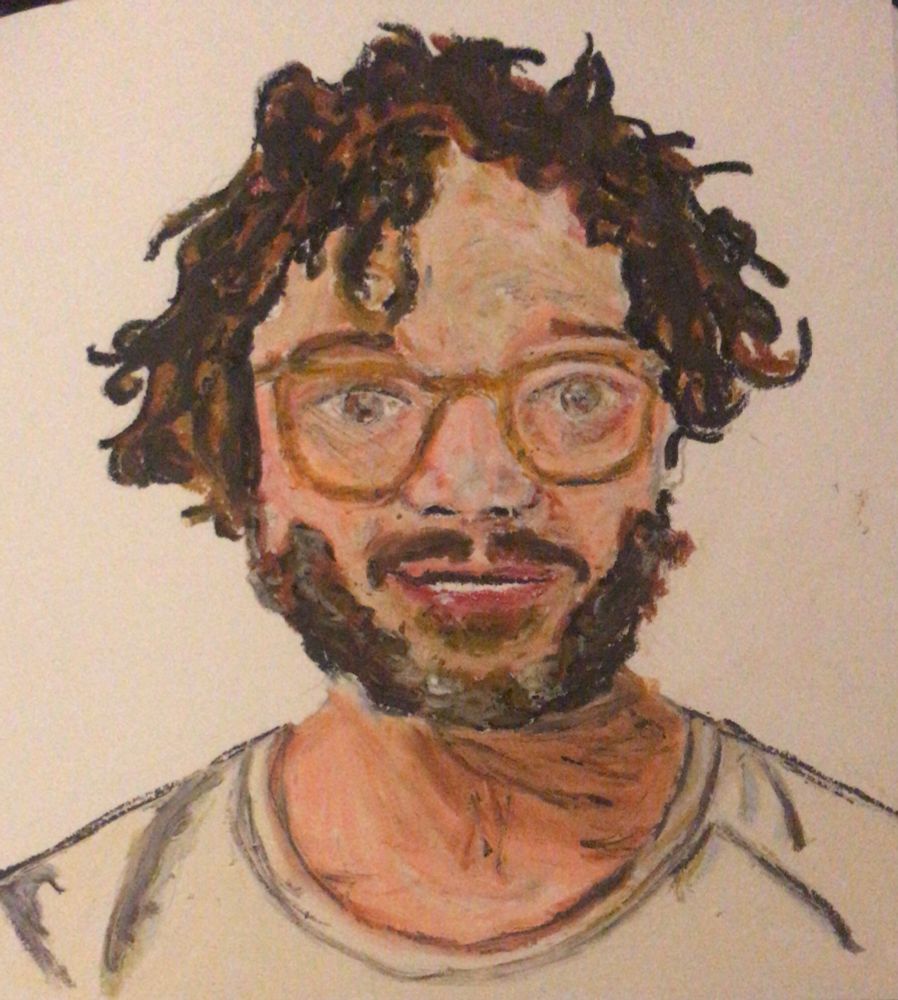 Portrait of a man with a beard, brown curly hair and glasses and a white t shirt.