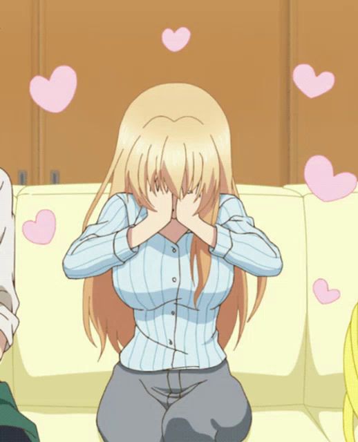 a blonde anime girl covering her face with her hands with pink hearts flying around her