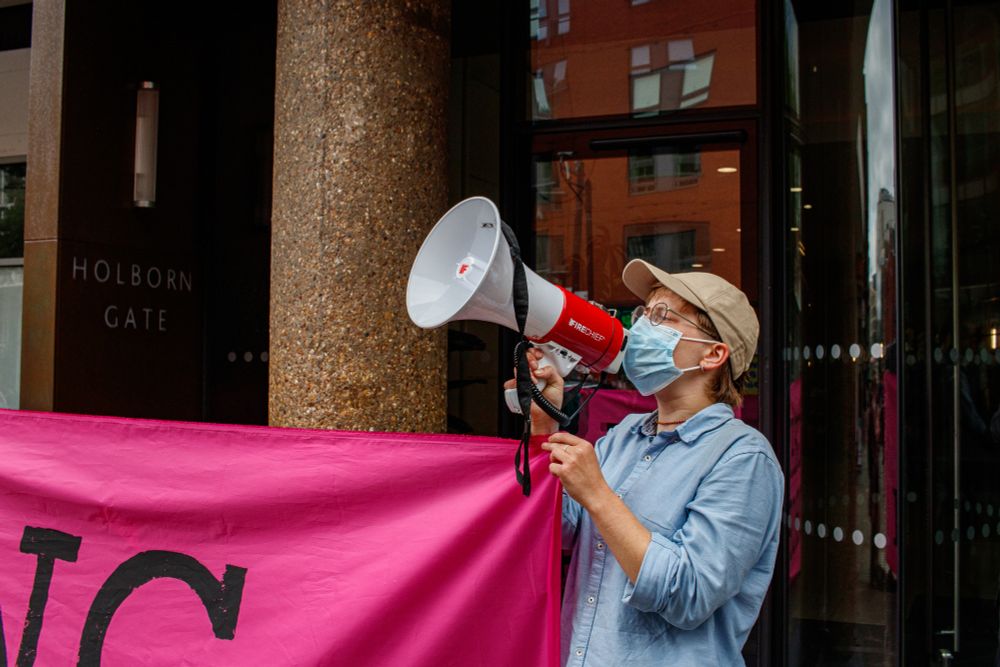 An Axe Drax activist in London holds a megaphone outside PR company Grayling's offices