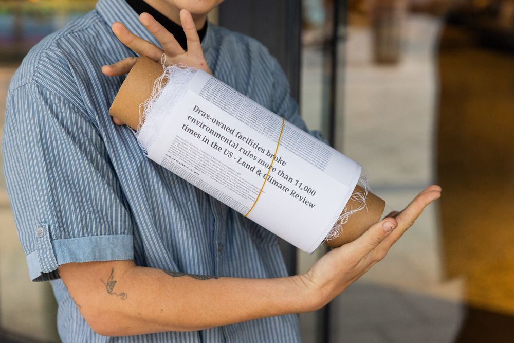 At lobbyist company Grayling in Leeds an activist from Axe Drax holds a scroll. The words "Drax owned facilities broke environmental rules more than 11,000 times in the US - Land & Climate Review.
Photo credit : Milo C