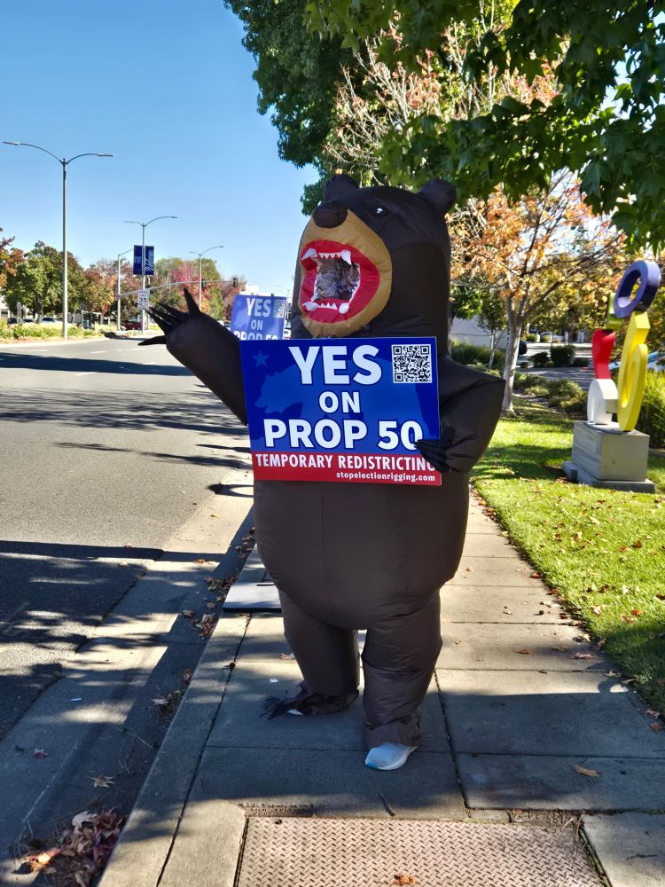 A bear holds a “yes on prop 50” sign