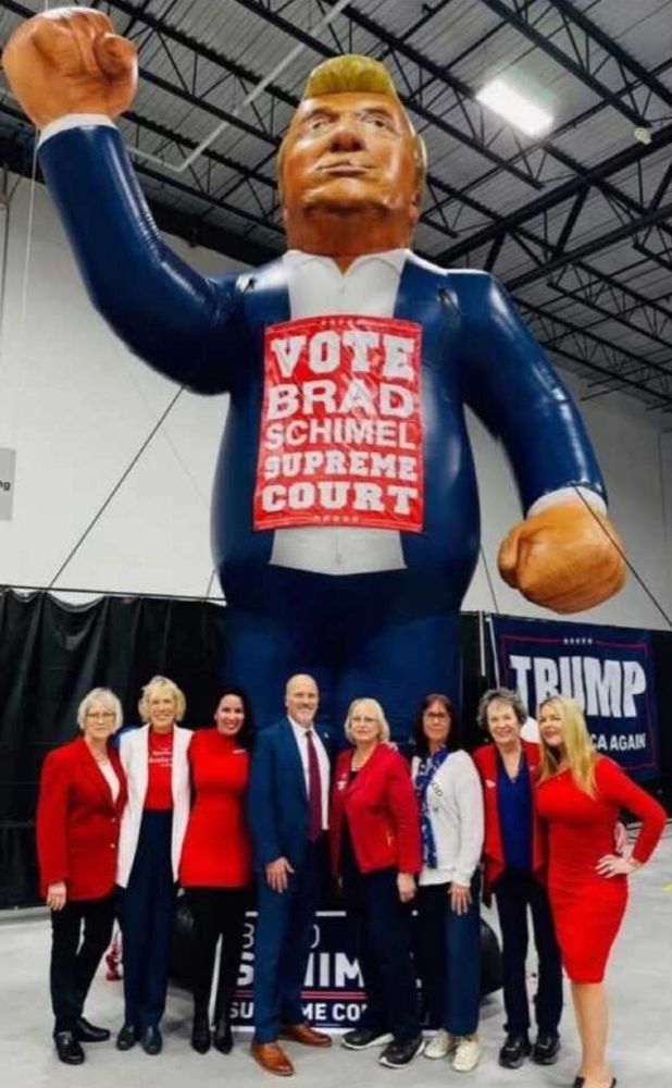 Brad Schimel and others in front of giant balloon in shape of Trump with giant fighting fists (lol) and a red sign saying VOTE BRAD SCHIMEL SUPREME COURT