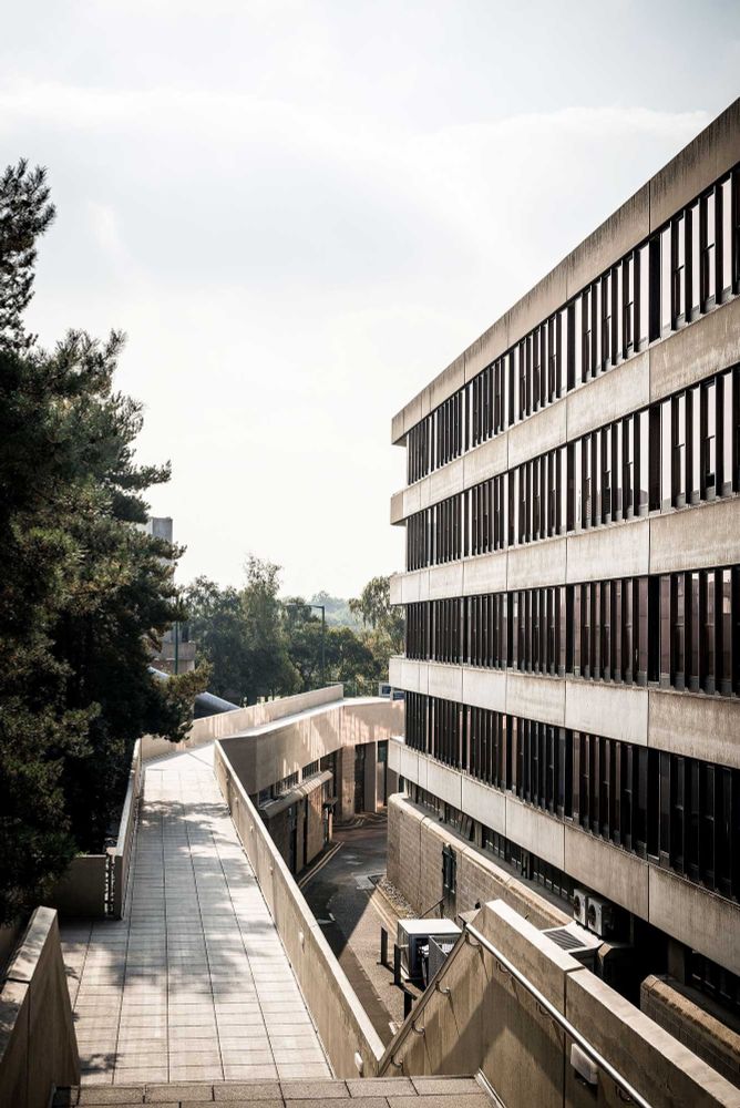 A different view down onto part of UEA's Teaching Wall and its walkway level, showing steps down, so the walkway level changes relative to ground level. Everything is made of concrete