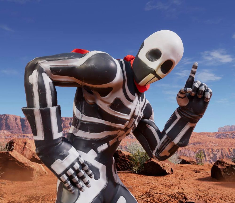 Skullomania, as he appears in the game Fighting EX Layer. He is a luchador in a skeleton costume with a red scarf around his neck. He stands against a desert backdrop, with one hand on his hip and the index finger of his other hand pointing up to the sky.