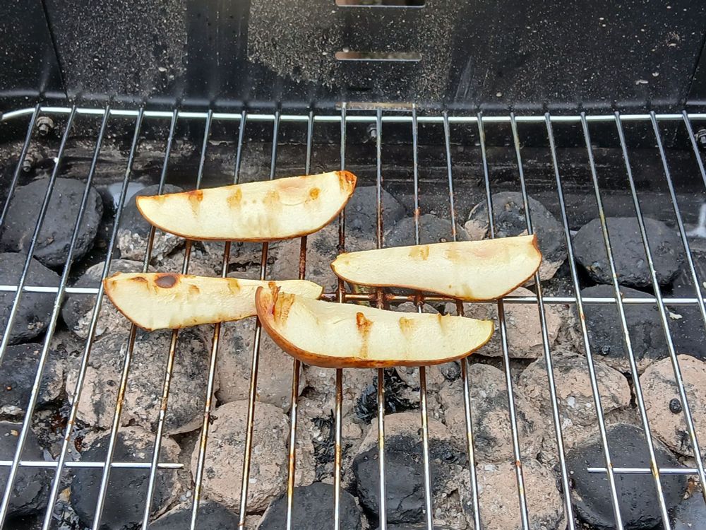 A quartered pear grilling on a barbecue