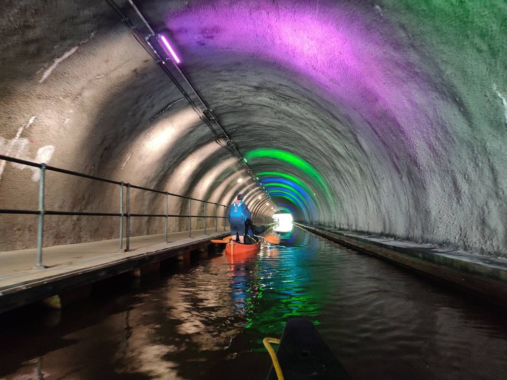 Round, rocky tunnel lit by coloured lights