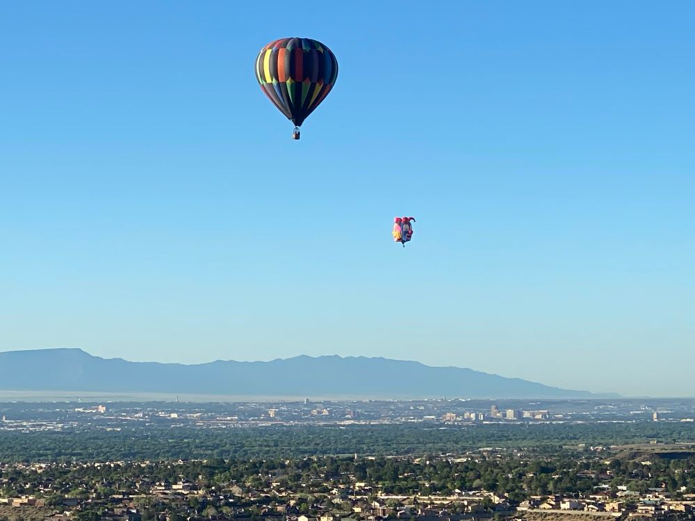 View of two balloons with city and mountain in background 