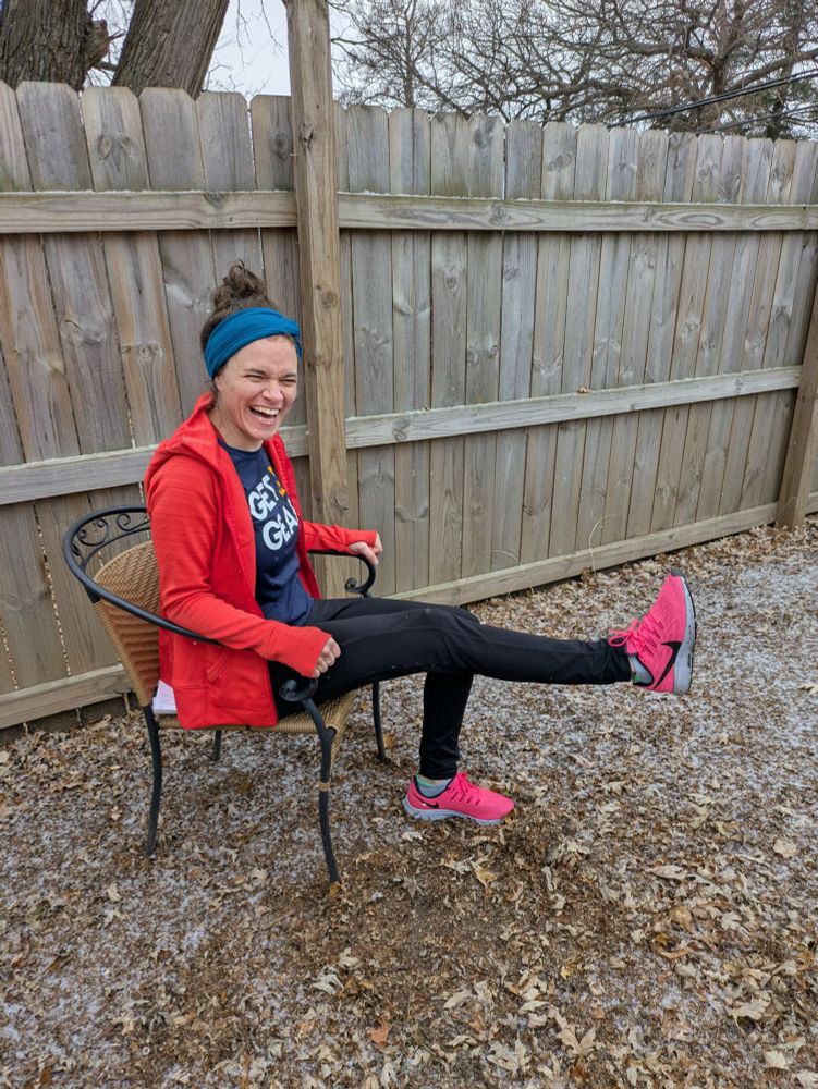 Doing seated leg lifts outside in light snow wearing hot pink shoes and bright orange jacket
