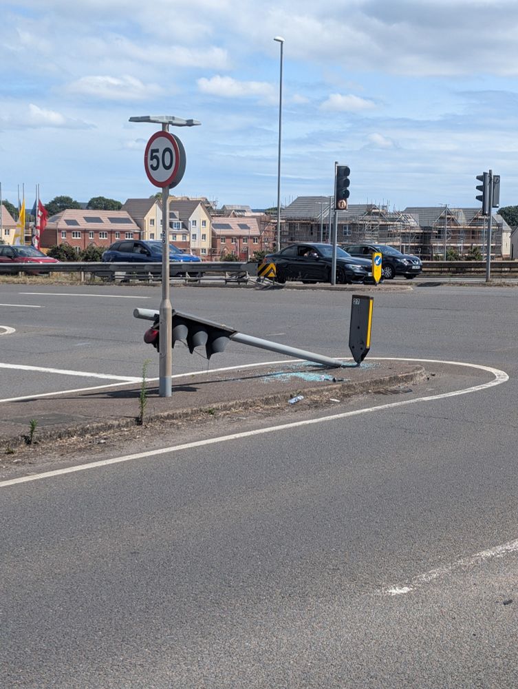 Photo of a traffic light at a junction that has been knocked down. 
