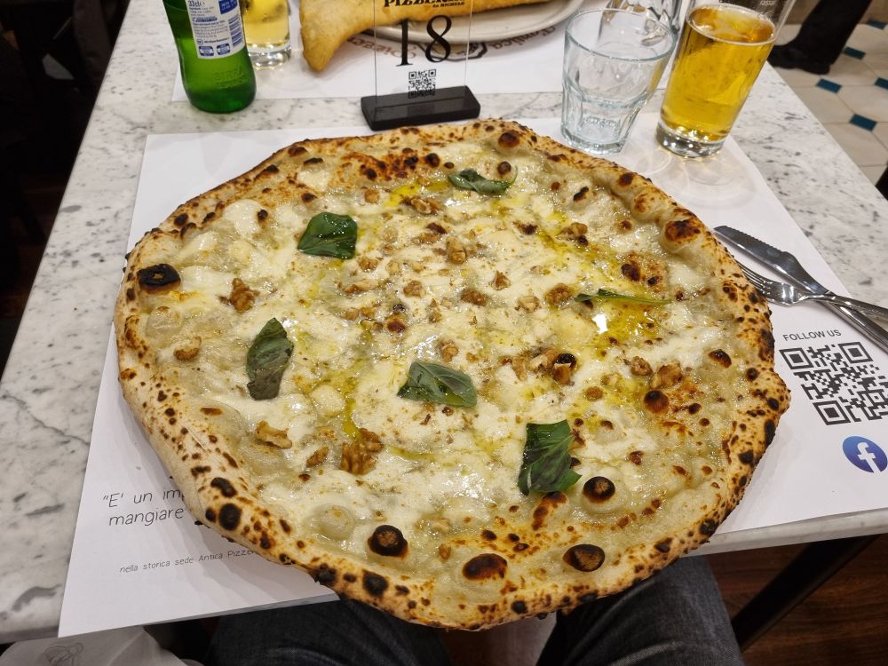 Foto einer Pizza mit 4 Sorten Käse. Die Pizza reicht über den Tellerrand.