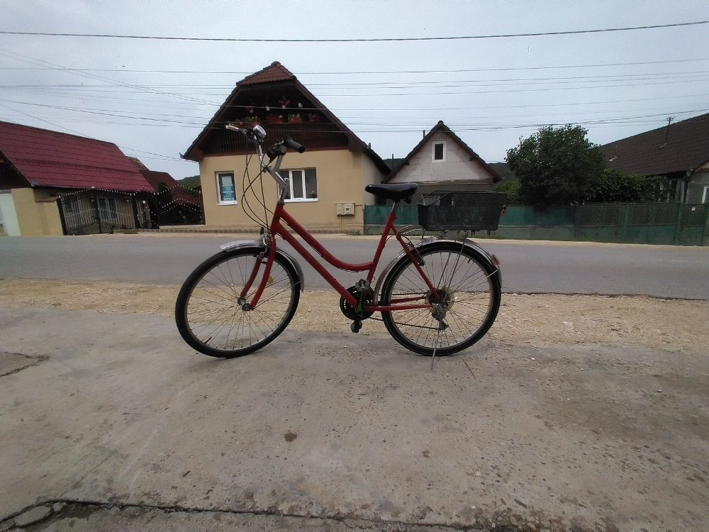 Left side view of a red bicycle for grownups parked on the side of a street