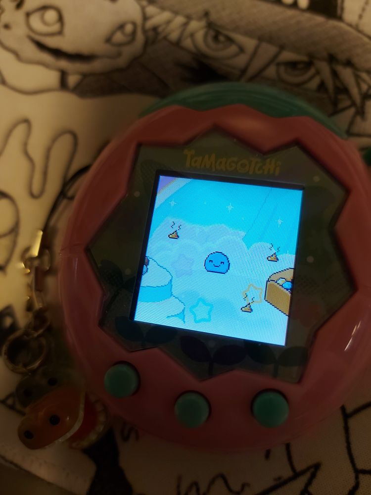 a photo of a Tamagotchi paradise. on the screen is a very happy baby tamagotchi surrounded by piles of poop.