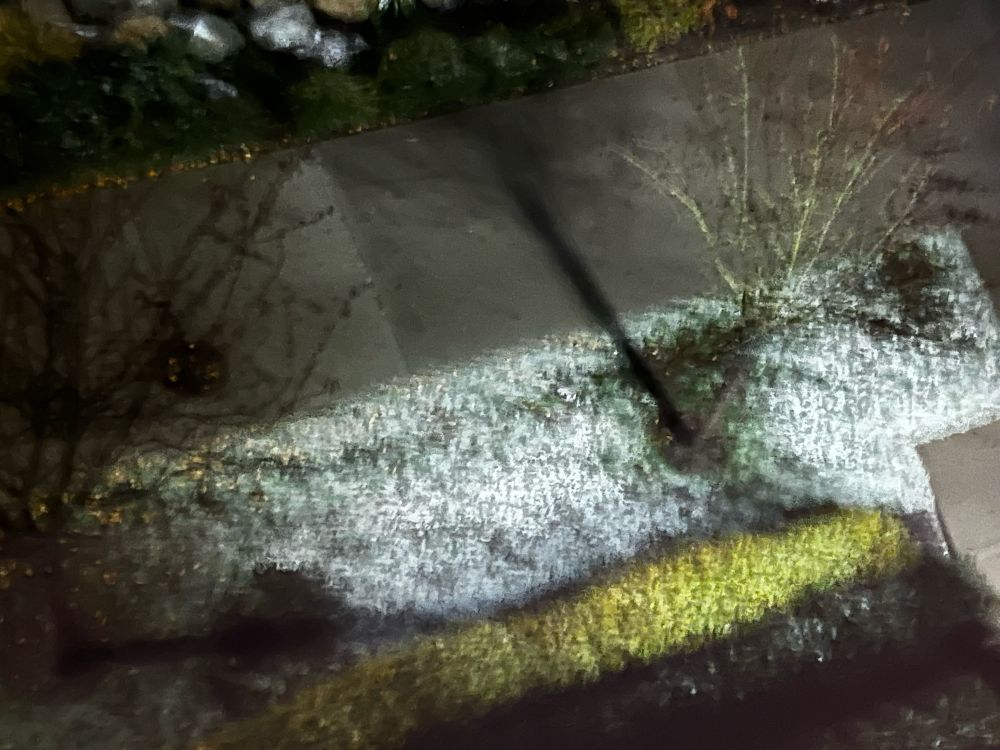 A grainy pic of snow on grass from a 5th story window