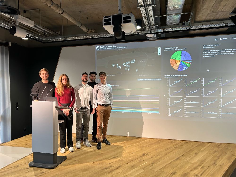 Student team on stage at Urban Tech Republic's exhibition center with their visualization on screen behind them.