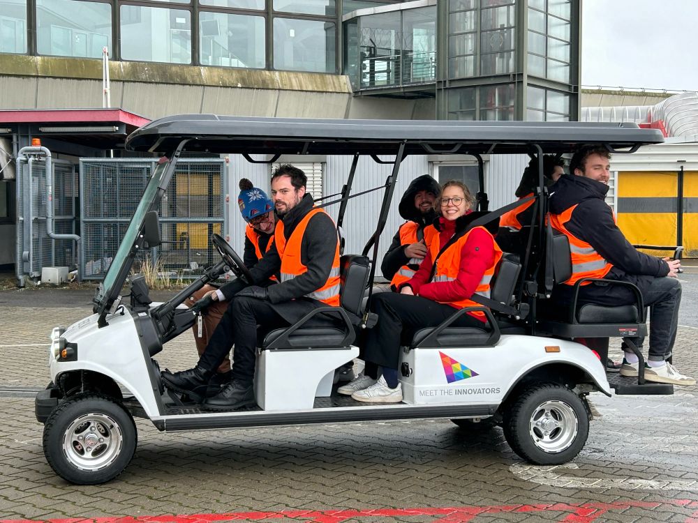 Students in high-visibility vests exploring the facilities on an airport cart.