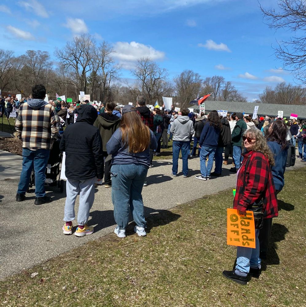 People with signs at small-town Hands Off forest rally